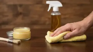 Mano che pulisce una superficie in legno con un panno e prodotti specifici per la cura del legno