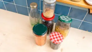 Vasetti riutilizzati contenenti legumi, pasta e cereali su un piano di cucina