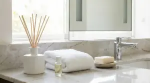 Asciugamani bianchi, sapone e diffusore su un lavandino da bagno in marmo