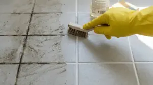 Pavimento con fughe sporche pulito con una spazzola da una persona con guanto di gomma