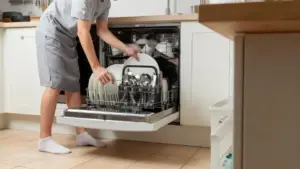 Persona che carica stoviglie e posate in una lavastoviglie da cucina