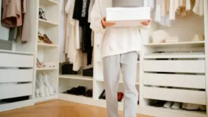 Persona in abbigliamento casual che tiene una scatola in un armadio ordinato