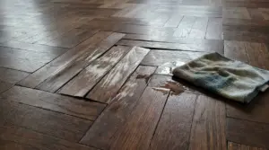 Parquet danneggiato con acqua e panno umido su una superficie in legno