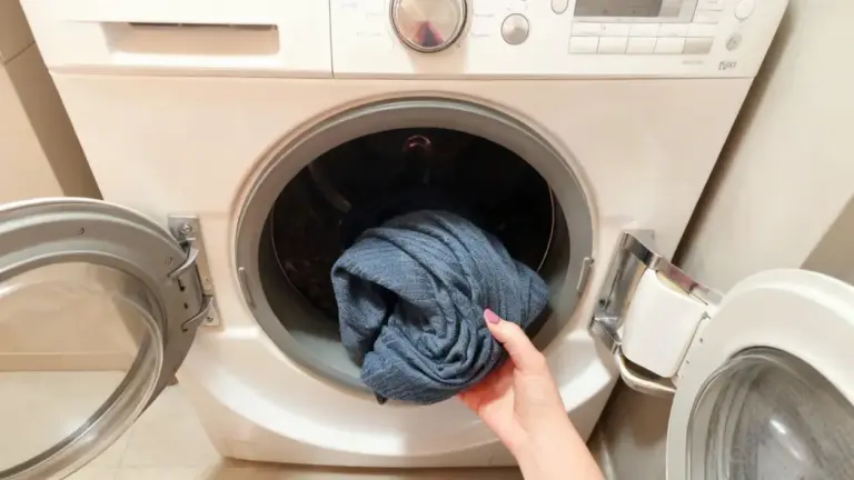 Una mano estrae un capo di abbigliamento da una lavatrice aperta