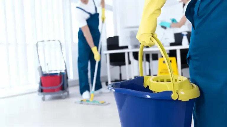 Persone con guanti e attrezzatura per le pulizie in un ambiente interno