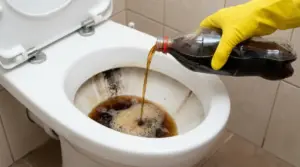 Una mano con guanto giallo versa cola in un water sporco